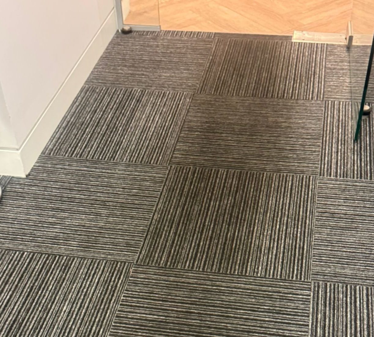 Heavily soiled office carpet tiles in Central London hallway before professional cleaning